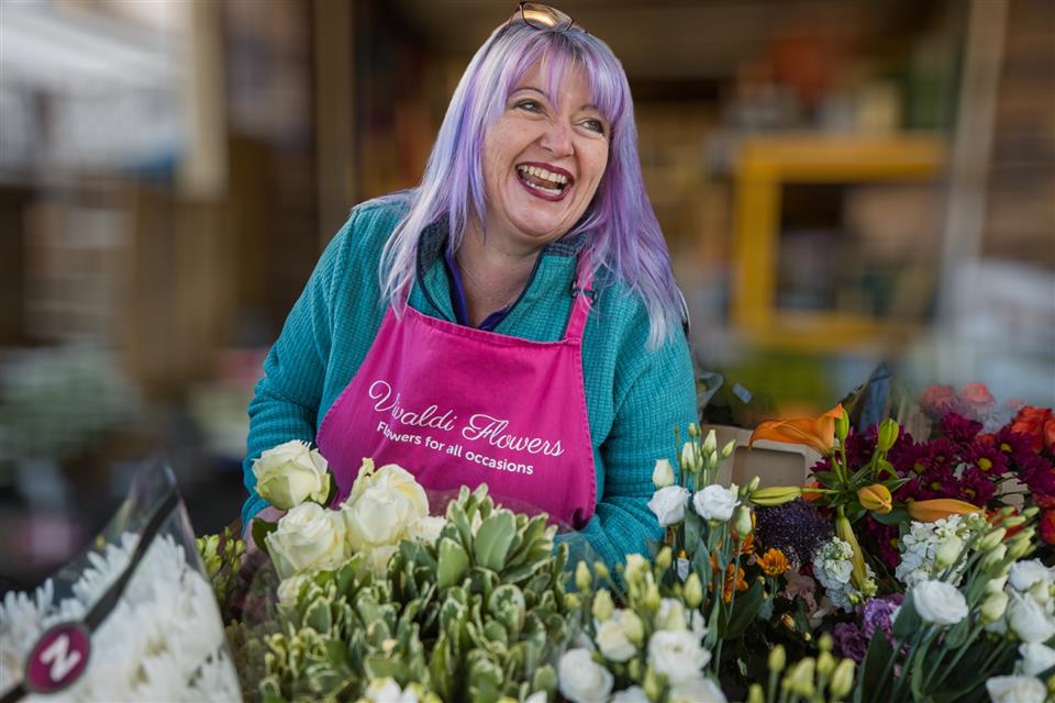 Nikki Pearce from Vivaldi Flowers with her Strelitzia Wedding and Events review. She's smiling with a selection of different flowers at her feet.